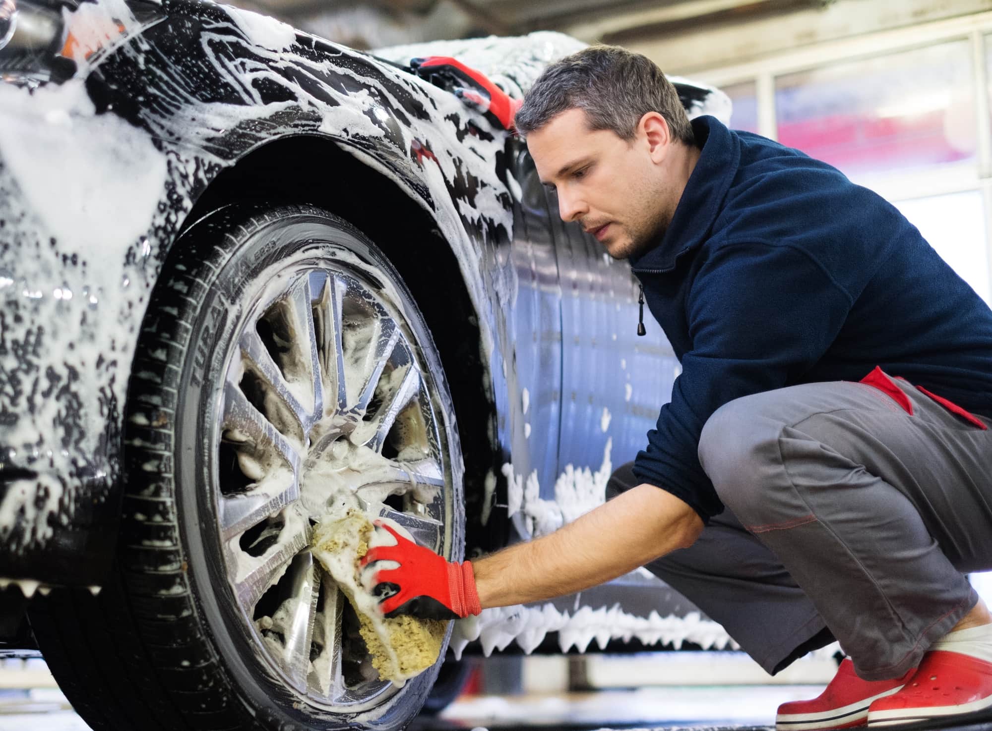 Autopflege Mann wäscht Autofelgen